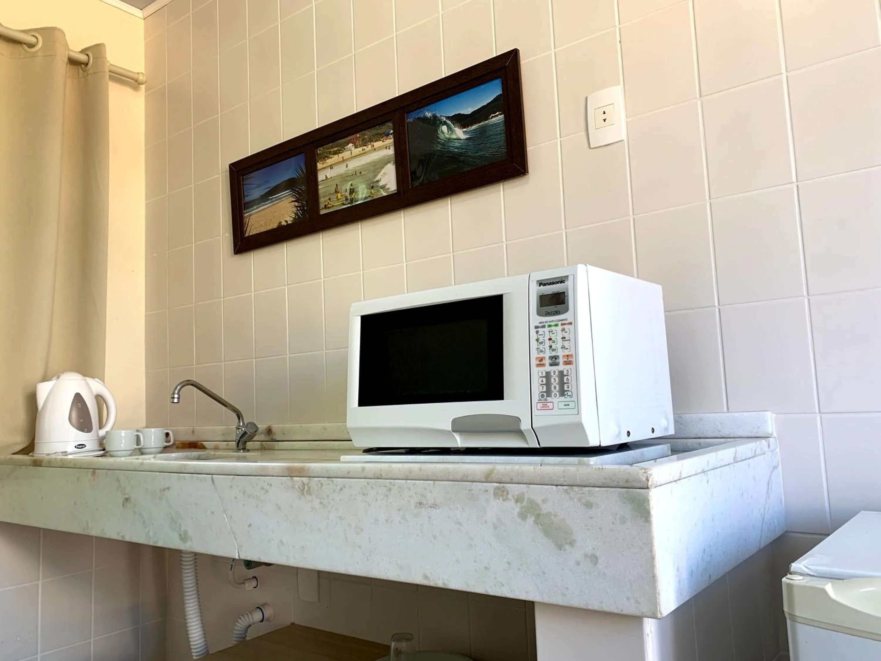 Bancada com chaleira, micro-ondas e utensílios no apartamento