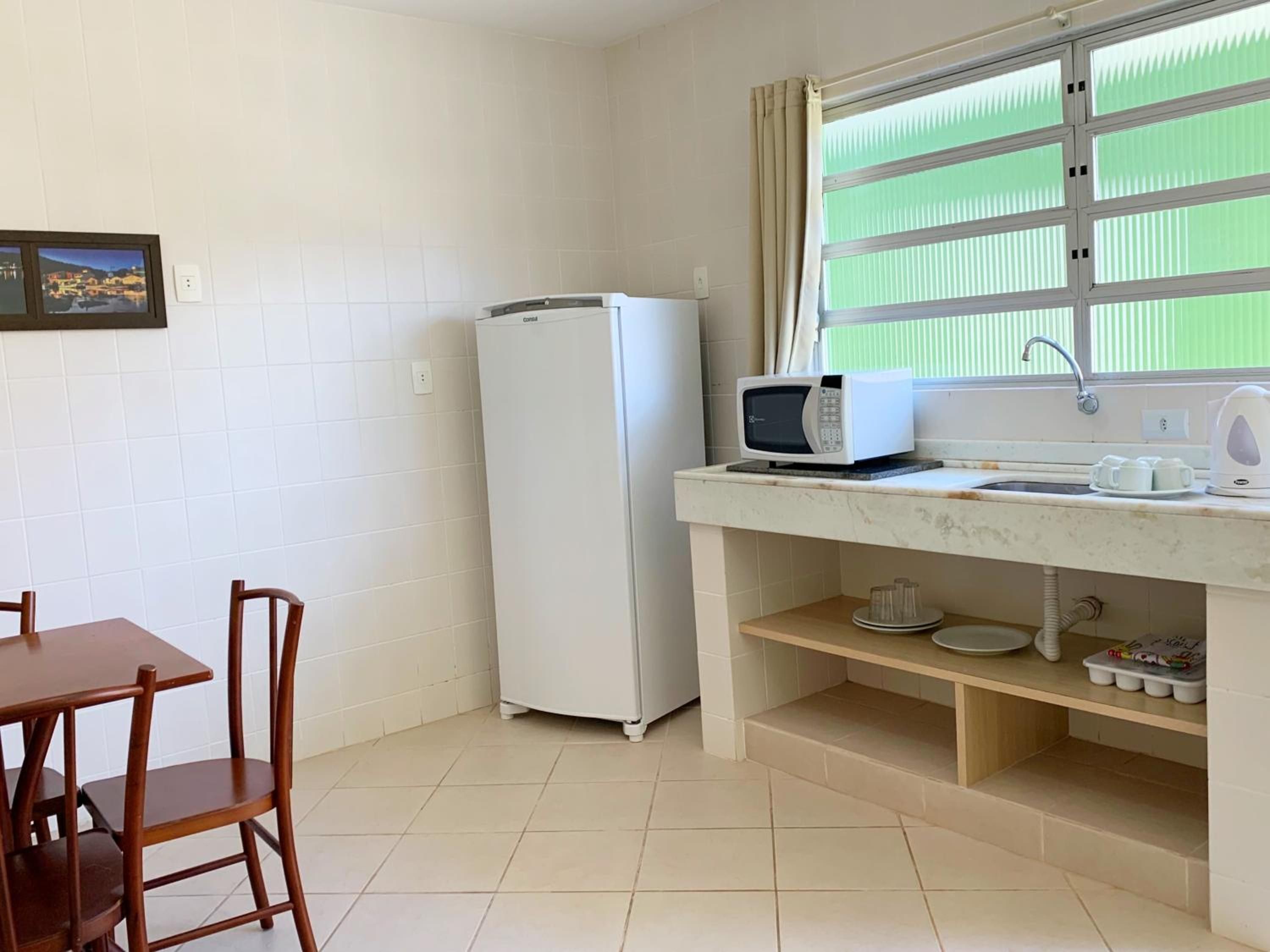 Cozinha completa do apartamento, com geladeira, micro-ondas, pia e mesa